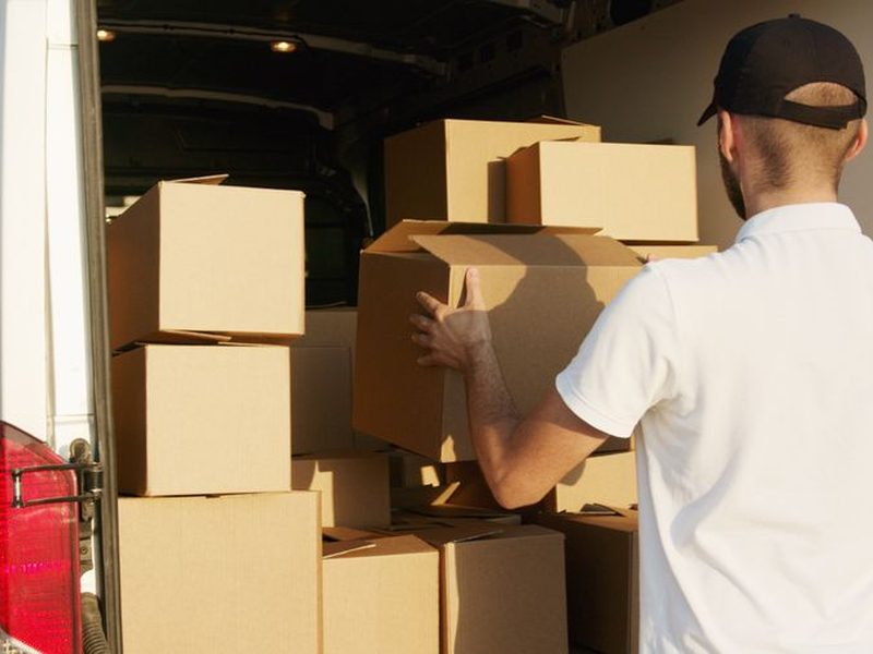 Uniformed courier loading boxes into a van